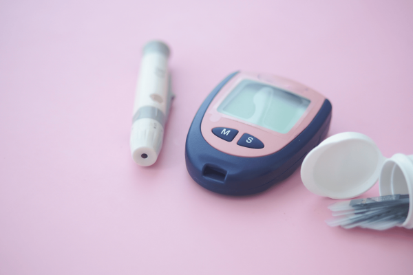 Blood glucose meter with lancet and test strips used for diabetes monitoring.