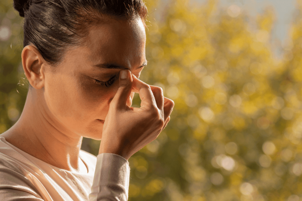 Woman pinching the bridge of her nose with eyes closed